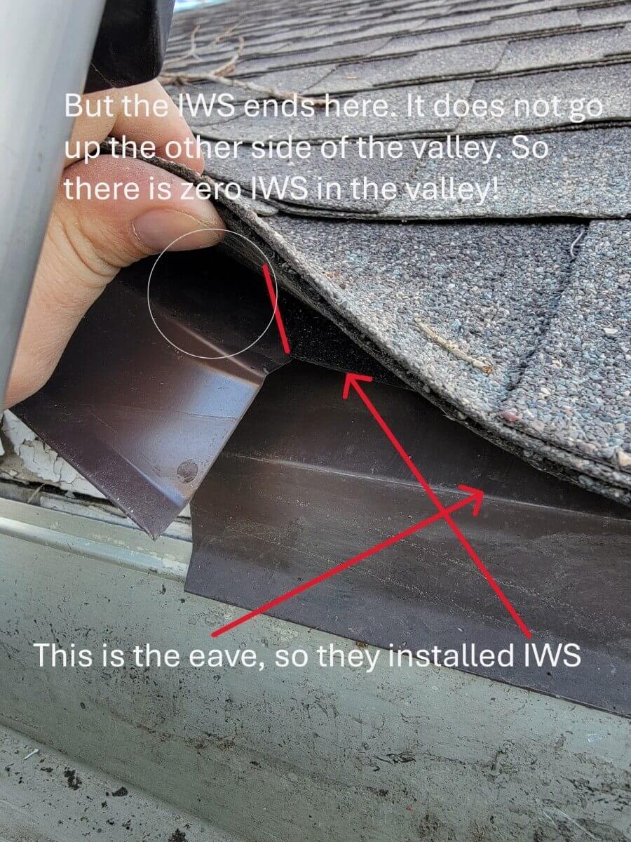 A finger lifting a shingle in a valley to show no Ice & Water Shield underneath.
