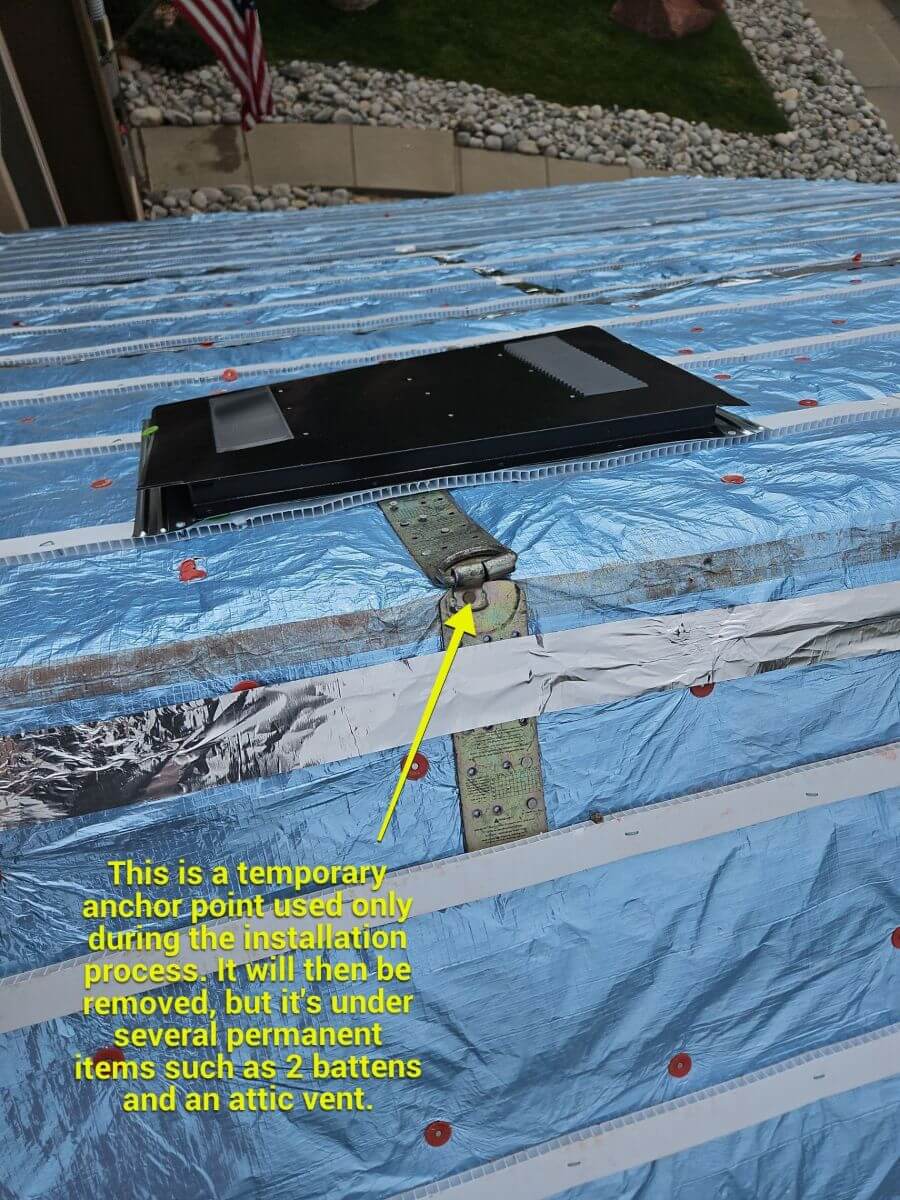 A temporary safety harness anchor point left installed underneath permanent roofing battens.